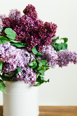Purple bouquet of lilac flowers in a stylish vase on wooden table