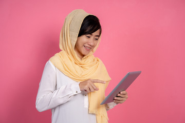 hijab woman using tablet pc over pink background