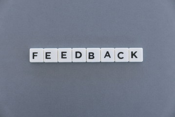 Feedback word made of square letter word on grey background.