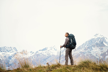 Man hiker in the mountains with a backpack, standing in profile. Active healthy lifestyle. Solo...