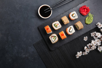 Set of sushi and maki rolls with branch of white flowers on stone table