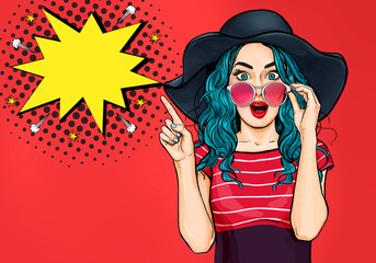 Pop Art Woman surprised in hat and glasses showing product .Beautiful girl with curly hair pointing to on bubble . Presenting your product. Expressive facial expressions - obrazy, fototapety, plakaty