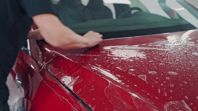 Pasting machine specially film. Car wrapping specialists straightening film to remove air bubbles
