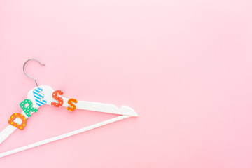 White hangers with dress text on pink background