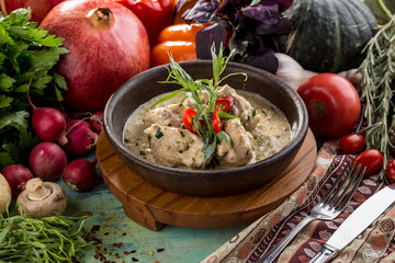 Baked chicken with grilled vegetables, greens and white sauce in pan on wooden table