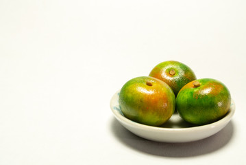 green orange in a bowl isolated on white background