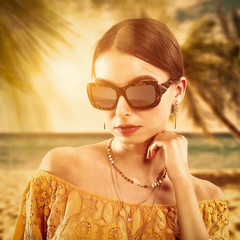 Fototapeta na wymiar Slim young woman in sunglasses on beach with palms. Ocean landscape with sunaset time and free space for your decoration. 