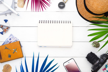 Summertime travel and vacation Background concept. Flat lay traveler accessories on white wooden background with smartphone, palm leaf, seashell, camera and accessories.  Top view with copy space.