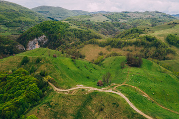 Drone view of green meadows, small houses and roads in Transylvania, Romania.