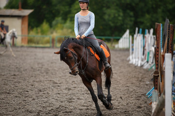 Young girl riding bay horse on equestrian sport training