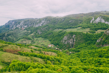 Fototapeta premium Drone view of green meadows, small houses and roads in Transylvania, Romania.