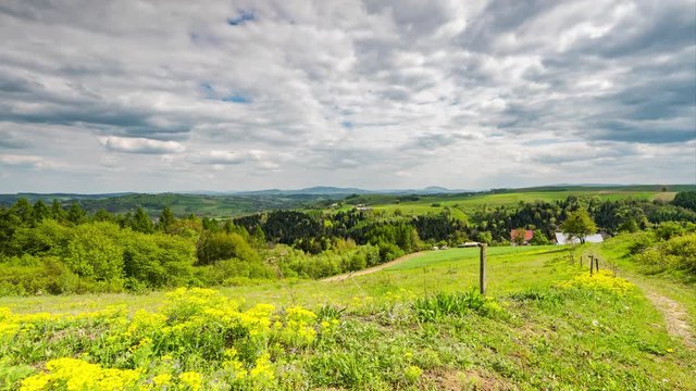Rolling hills and meadow in rural countryside with fast moving clouds at summer time. 4K time lapse.