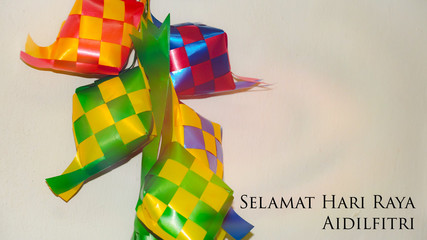 Greeting with malay word "Selamat Hari Raya Aidilfitri" that translates to wishing you a joyous hari raya on ketupat ribbon background. Selected focus. Image flare, soft, bokeh and vintage.