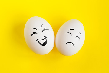 Two white eggs on yellow background concept. Emotions laughter and sadness. Friendship, relationship concept