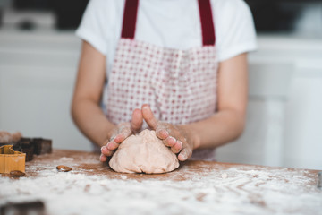 Girl kneading raw dough on table closeup. Cooking at kitchen.