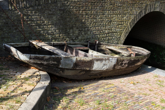 old wooden boat on shore, near brick bridge. Oudewater, The Netherlands