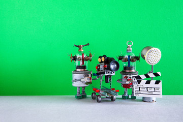 Funny robot cameraman clapperboard spotlight assistant shoots dramatic comedy with elements of a horror movie, action adventure film. Motion picture robotic filmmaking backstage. Green background