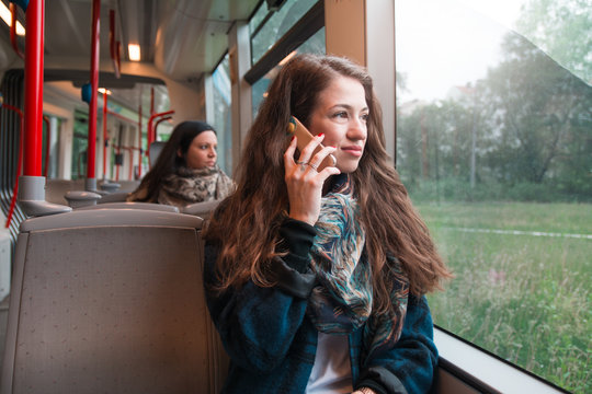Young businesswoman gazing out window while riding public transportation commuter train
