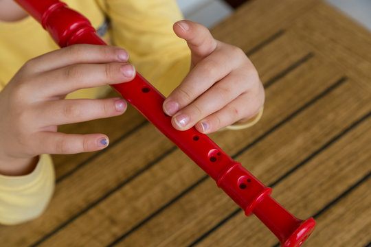 child playing and tuning red flute in a music school for education concept