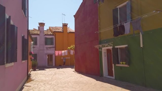 panning shot of colorful houses in Burano with a clothesline which hangs on  front of the house at sunny weather, Italy
