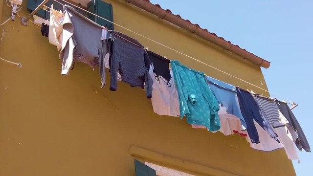 shot of colorful houses in Burano with a clothesline which hangs on  front of the house at sunny weather, Italy