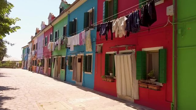 shot of colorful houses in Burano with a clothesline which hangs on the window and in front of the house at sunny weather, Italy
