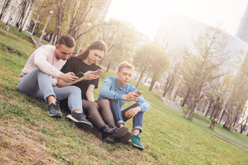 Naklejka na ściany i meble The group of young friends teenagers using mobile at the city street
