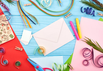Envelope on blue wooden table with flowers, color pencils and cardboards