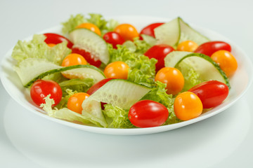 healthy vegan lunch with green salad and red yellow tomatoes on a white background