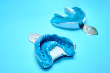 Two dental impressions on a blue background with copy space. Dental molds from the upper and lower jaws of silicone material. The imprint of the tooth row of high precision. © baklykovadaria