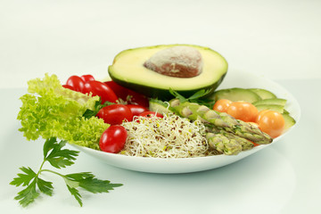 Fresh vegetarian mixed lunch with avocado, tomatoes, sprouts, asparagus and phasalis on a white background