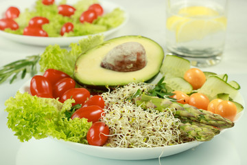 Fresh vegetarian mixed lunch with avocado, tomatoes, sprouts, asparagus and phasalis on a white background