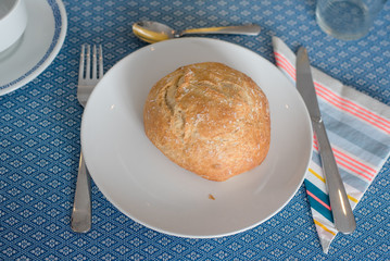 Plate with fresh crusty bread and glass of juice on white plate