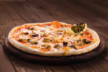 delicious Italian seafood pizza on a dark wooden table (close).