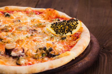 delicious Italian seafood pizza on a dark wooden table (close).