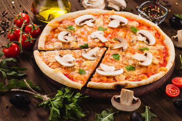 italian pizza with chicken and mushrooms on the wooden dark background (close). Cut one piece