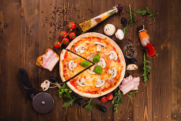 italian pizza with ham and mushrooms on the wooden dark background (close top view). Cut one piece