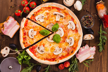 italian pizza with ham and mushrooms on the wooden dark background (close top view). Cut one piece