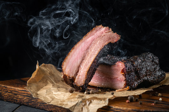 Smoky sliced beef brisket with dark crust from classic Texas smokehouse on a dark background