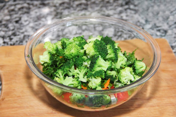 green broccoli salad in a glass plate on a wooden board background