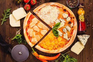 Classic Italian Four Cheese Pizza with Mozzarella, Brie, Dor Blue, Radamir on a dark wooden background with ingredients around (close top view). Cut one piece