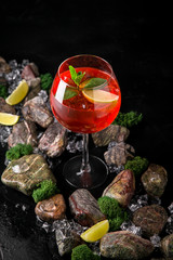 Fototapeta na wymiar Aperol syringe soft alcoholic drink on a black background with stones and ice. Cocktail card for a bar or restaurant.
