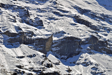 snow and ice covered cliff of swiss alps mountain in sunlight