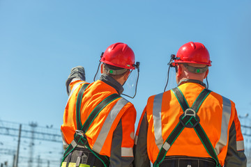 Two workers linemen look on power lines