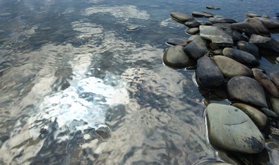 The sky and clouds are reflected in a big puddle after a heavy rain, the background