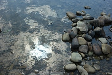The sky and clouds are reflected in a big puddle after a heavy rain, the background