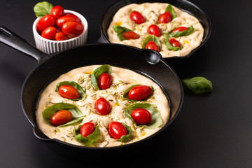 Food concept rising dough for vegan Homemade organic Focaccia in skillet iron pan on black background with copy space