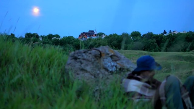 Cowboy sleeping at big rock at valley with full moon at sky