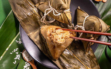 Zongzi, woman eating steamed rice dumplings on green table background, food in dragon boat festival...