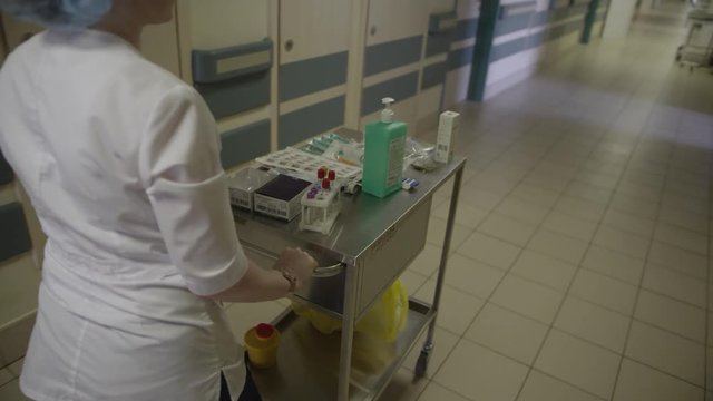 Nurse rolls a medicine trolley down the hall